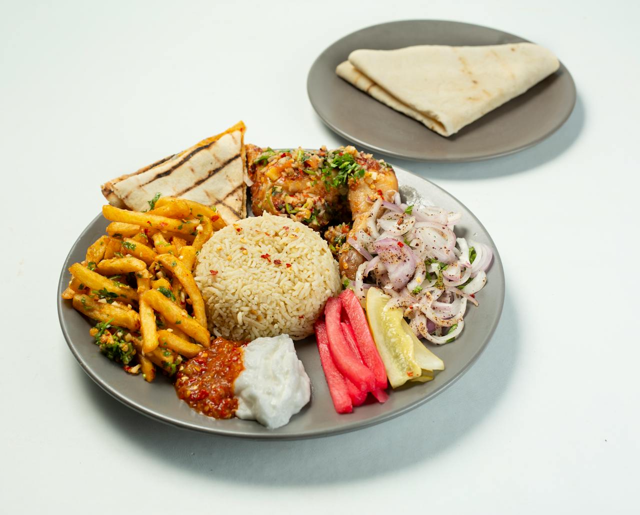 hero-img-02 A vibrant Middle Eastern feast featuring chicken, rice, and fresh veggies on a plate.